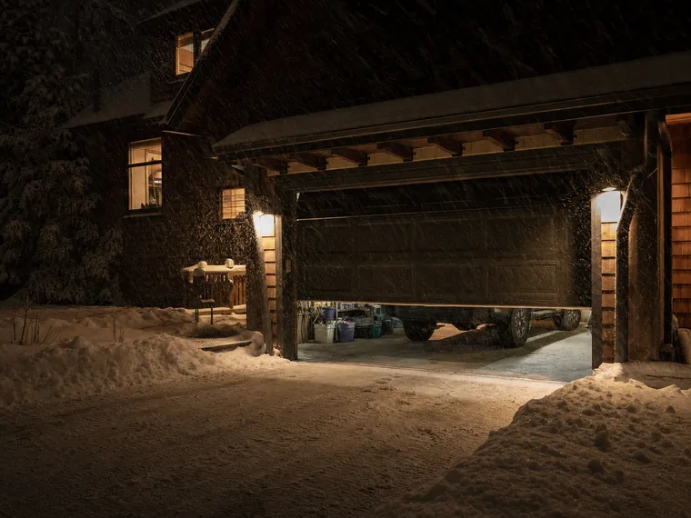 Garage door half-open on a snowy Marquette night, heavy snow falling through the porch light
